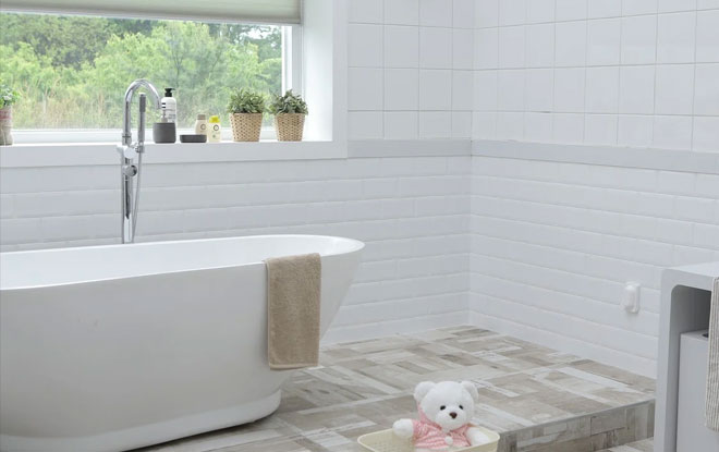 A freestanding bath with white tiles on the wall